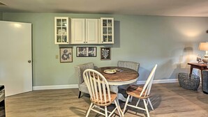 A dining area with a round wooden table, two upholstered chairs, and a cabinet with glass doors.