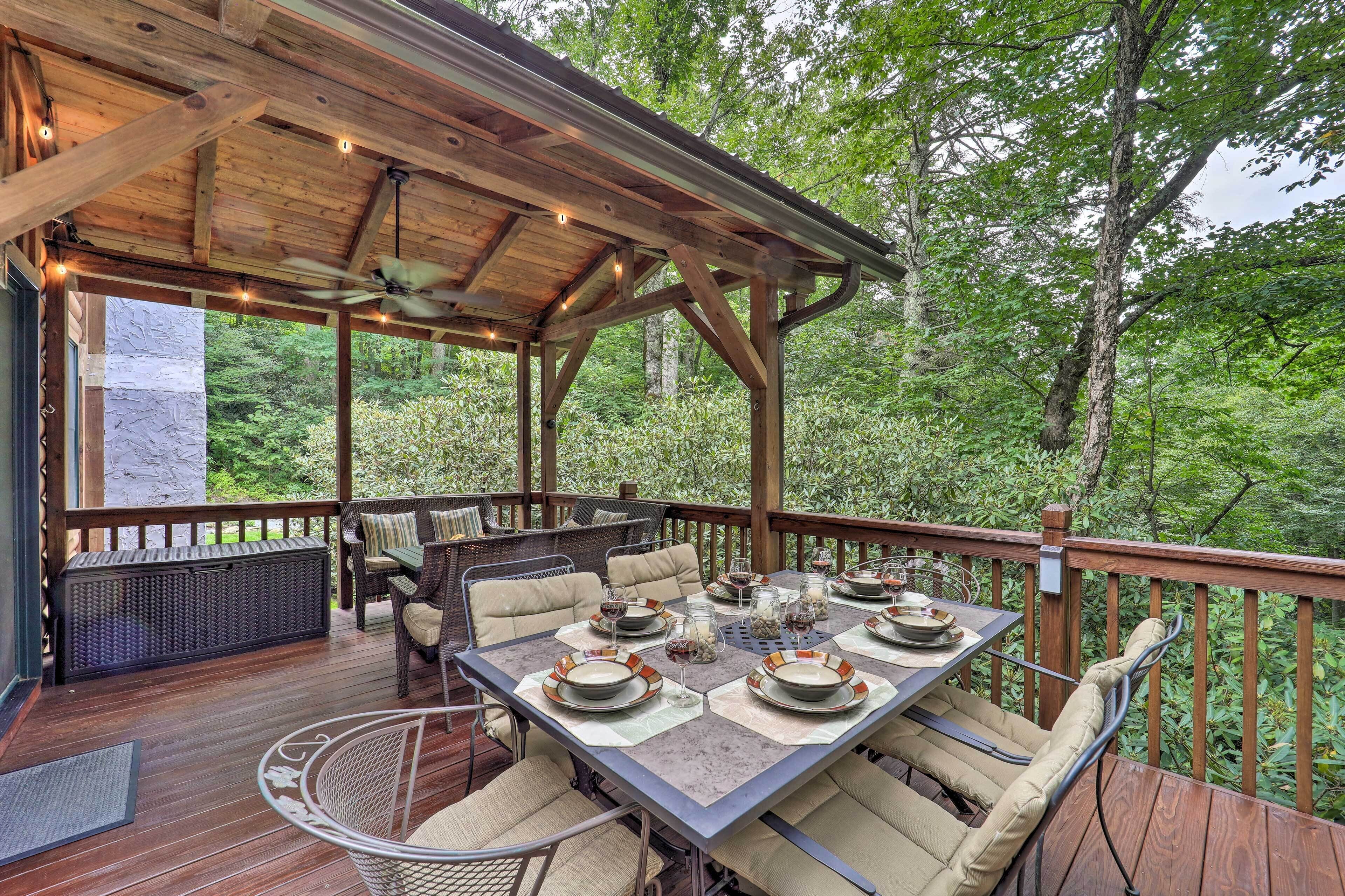 An outdoor deck with a wooden pergola, dining table set for four, and wicker furniture.