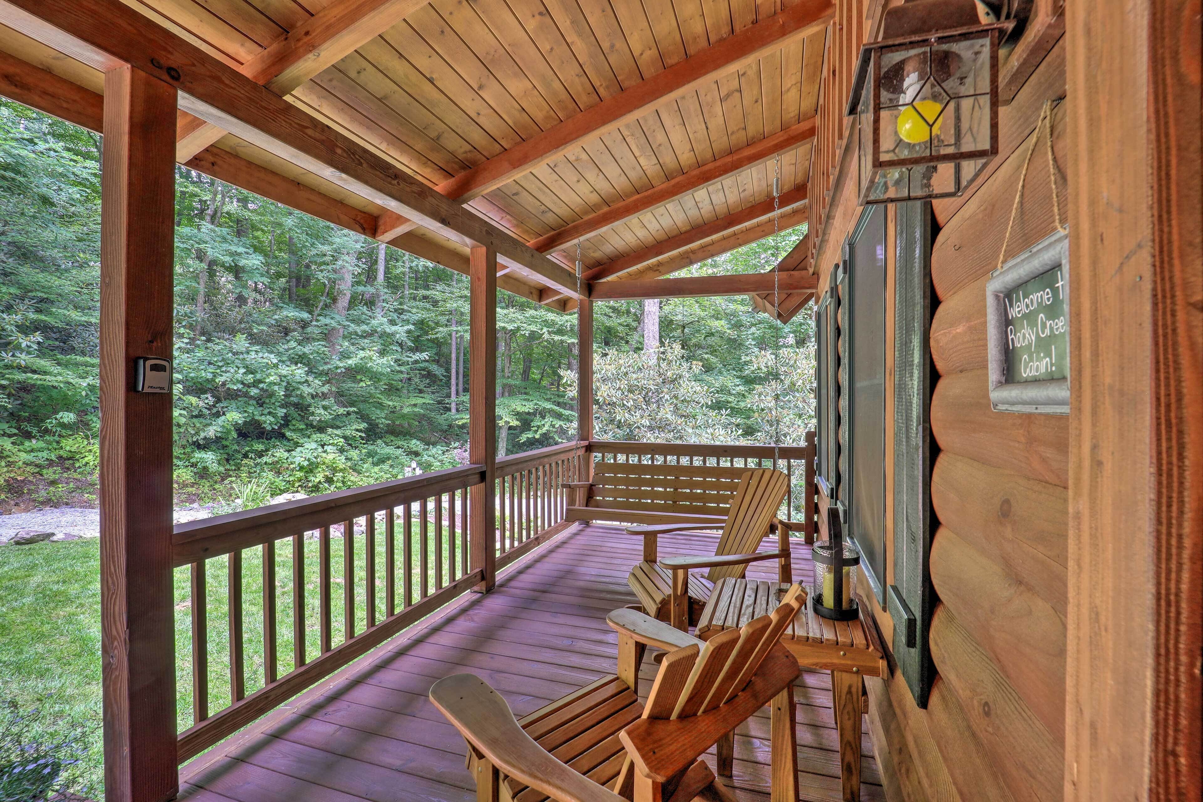 A wooden deck with Adirondack chairs and a sign welcoming guests to Rocky Creek Cabin.