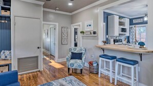 A modern kitchen with a bar area, wooden flooring, and a ceiling fan. - Central Cottage w/ Grill, 1 Mi to Cajun Field (Lafayette)