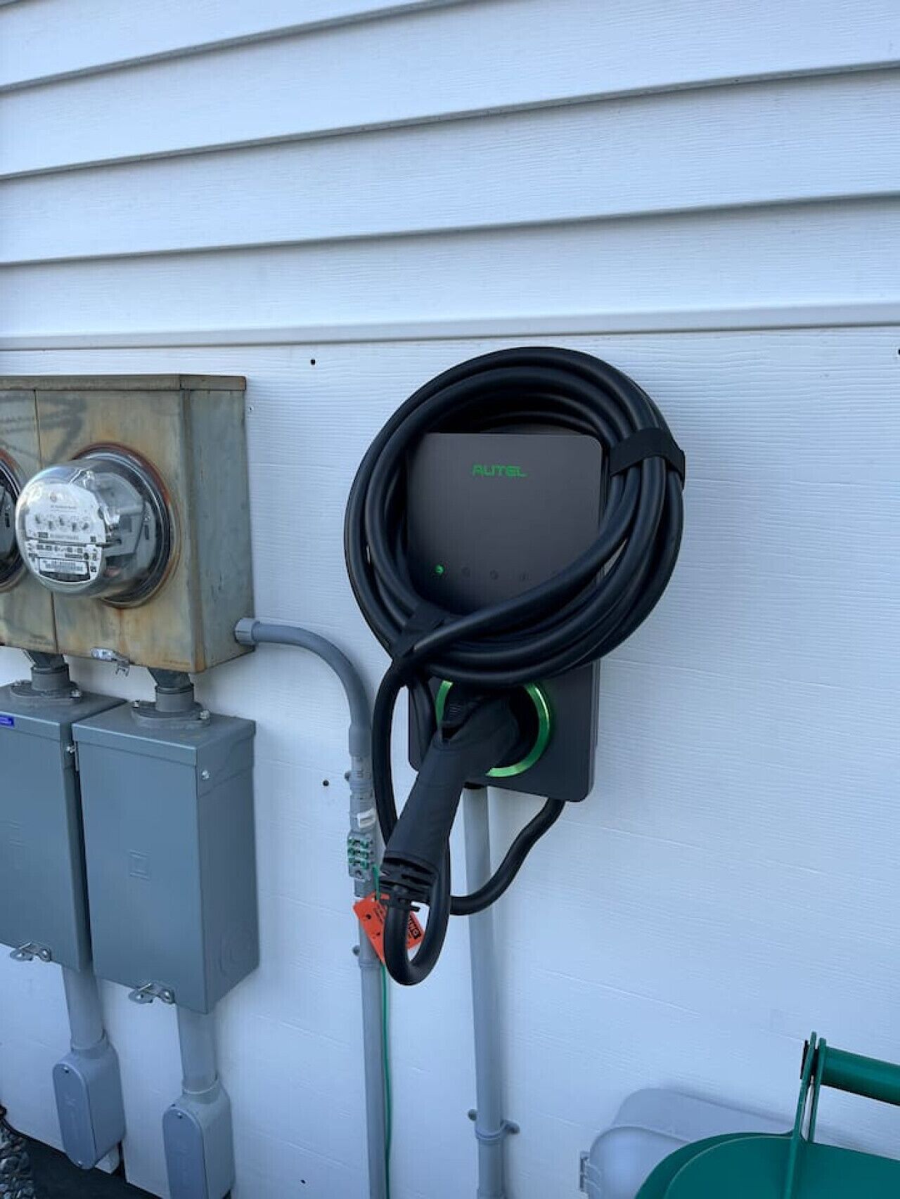 An outdoor electrical outlet with a cable connected to a device labeled "AUTEL".