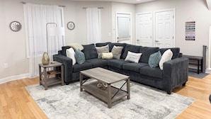 A modern living room with a sectional sofa, a coffee table, and a side table. - Modern, All New 3BR Near UMASS (Lowell)