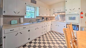 A kitchen with white cabinets, a checkered floor, a toaster, a coffee maker, and a fire extinguisher.