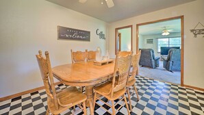A dining area with a wooden table and chairs, a ceiling fan, and a checkered floor.
