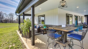 Une terrasse extérieure avec une table et des chaises en bois, un luminaire suspendu et une vue sur les environs.