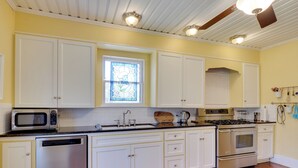 A kitchen with white cabinets, a stainless steel dishwasher, a microwave, a stove, and a sink. - Charming Georgetown Home - Walk to Downtown! (Georgetown)