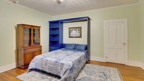 A bedroom with a bed, a ceiling fan, a wooden cabinet, a blue shelving unit, and a white door. - Charming Georgetown Home - Walk to Downtown! (Georgetown)