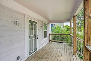 Um deck de madeira com porta e janelas brancas.