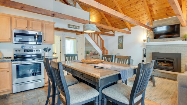 A spacious kitchen with wooden beams, a large dining table, and a fireplace.
