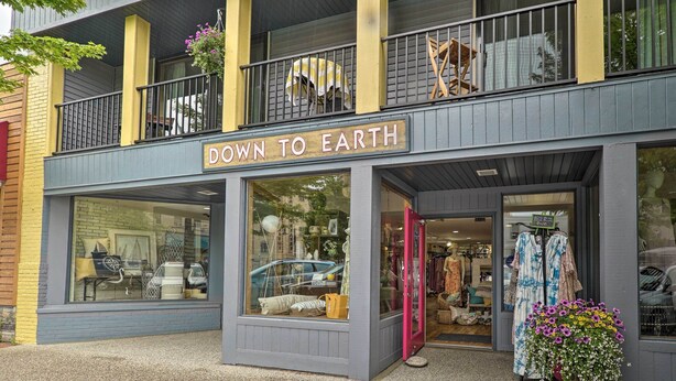 A storefront with a sign reading "DOWN TO EARTH" and a display window with various home decor items. - Cute Grand Haven Apartment: Walk Downtown Streets! (Grand Haven)