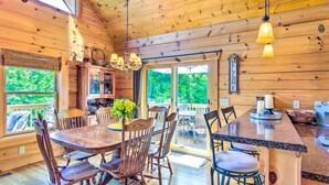 Ein Holzblockhaus-Interieur mit Essbereich, Küche und einem großen Fenster.