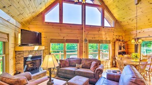 Ein gemütliches Blockhaus-Interieur mit Kamin, Ledersofas, einem Fernseher und einem Essbereich.