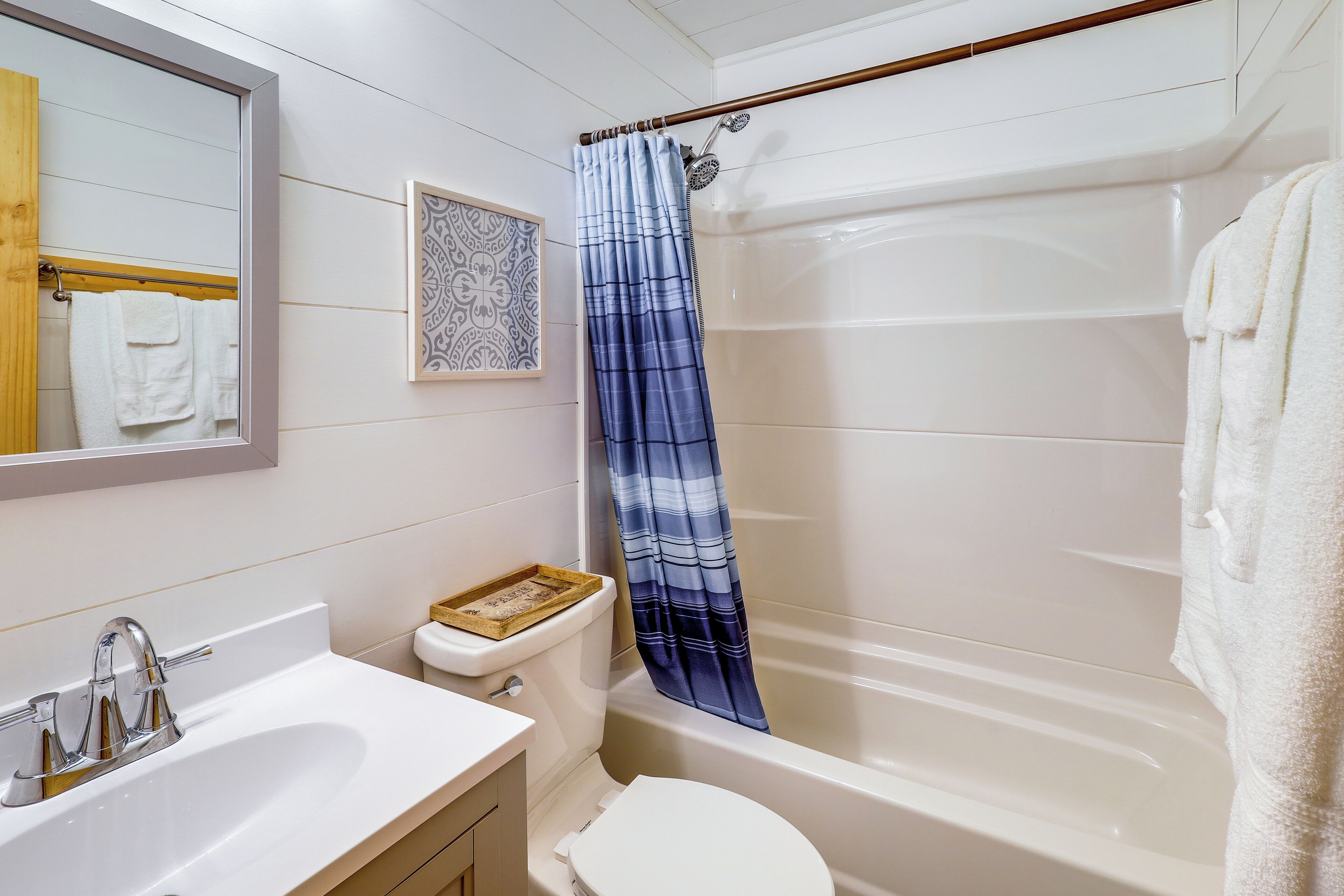 A bathroom with a white sink, a toilet, a bathtub, and a shower curtain.