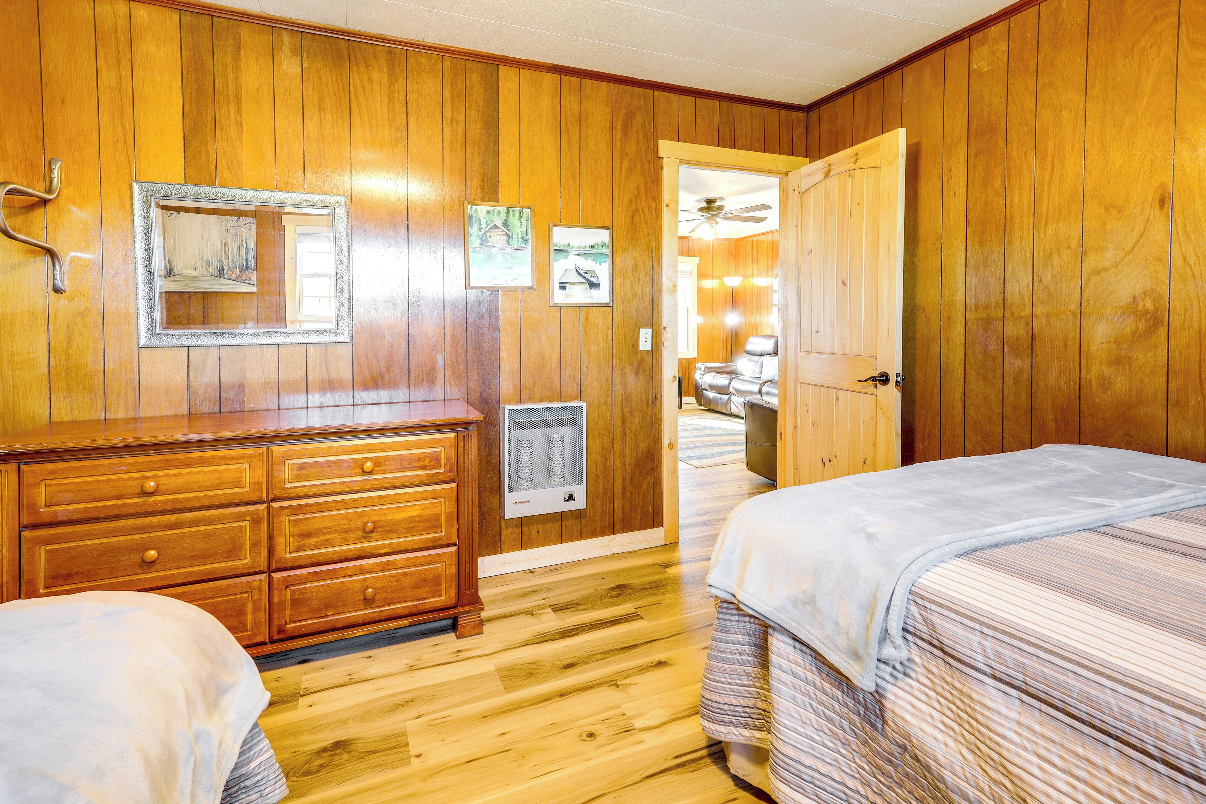 A wooden-paneled room with a bed, a dresser, and a mirror on the wall.