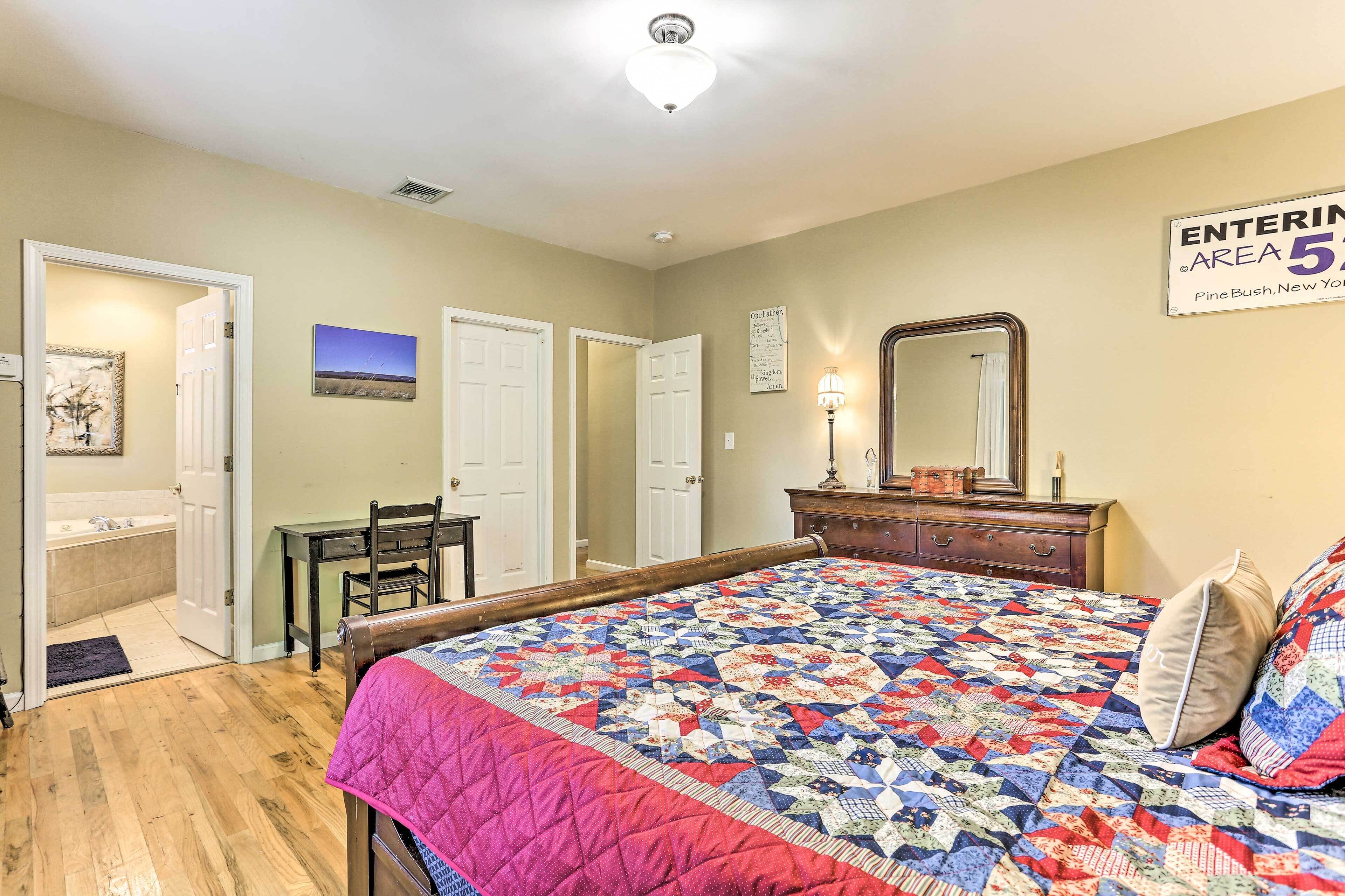 A bedroom with a large bed, a desk, and a chair. There is a sign indicating the area is 5.