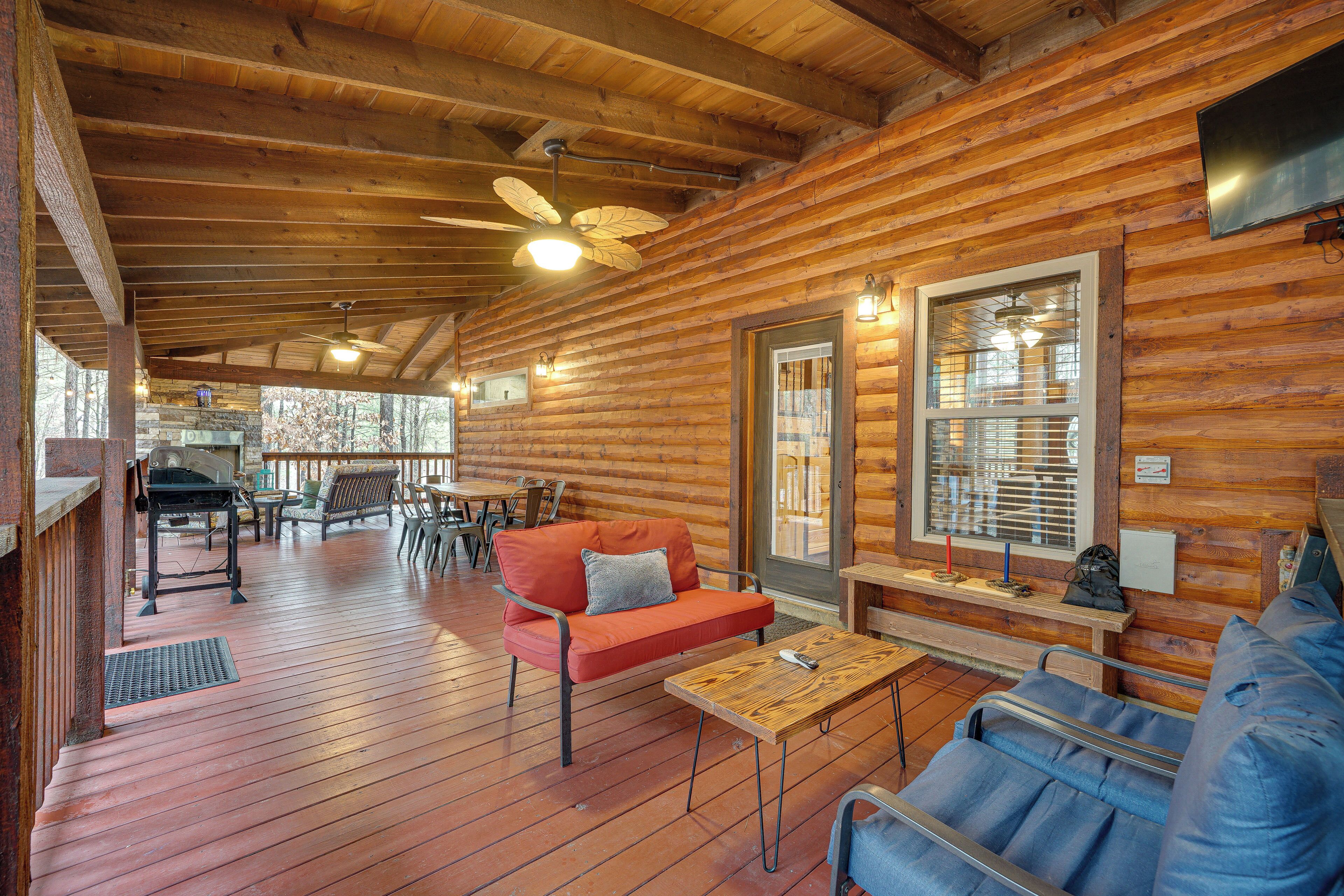Ein Holzblockhaus im Inneren mit Holzboden, einem roten Sofa, einem blauen Schlafsofa, einem Holztisch und einem Deckenventilator.