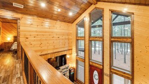 Ein Holzblock-Innenraum mit Kamin, großen Fenstern und einer Holztreppe.