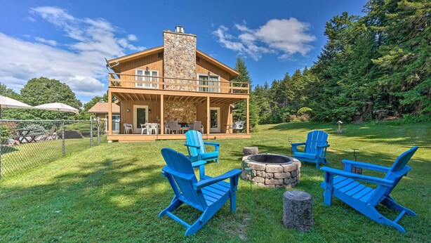 A wooden cabin with a stone chimney, a covered patio with outdoor seating, and a fire pit. - Family Winter Retreat w/ Hot Tub: 14 Mi to Slopes! (Whitingham)