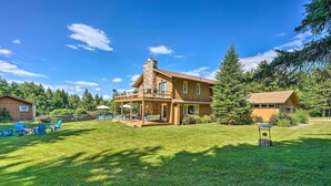 A large wooden house with a balcony, surrounded by a well-maintained lawn and trees. - Family Winter Retreat w/ Hot Tub: 14 Mi to Slopes! (Whitingham)