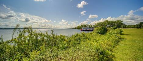 A grassy area with a body of water and a boat in the distance.