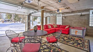 Une pièce avec un canapé rouge, une table ronde entourée de chaises et un tapis à motifs.