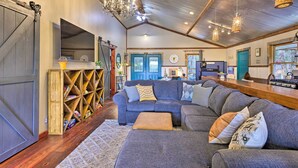 A spacious living area with a large sectional sofa, a wooden shelving unit, and a chandelier. - Pet-friendly Outdoor Paradise w/ Grill, Decks (Tabor)