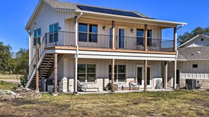 A two-story house with a balcony, a covered porch, and a stone foundation. - Dog-friendly Apartment ~ 32 Mi to Fort Worth! (Godley)