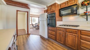 A kitchen with wooden cabinets, a refrigerator, a microwave, and a stove.