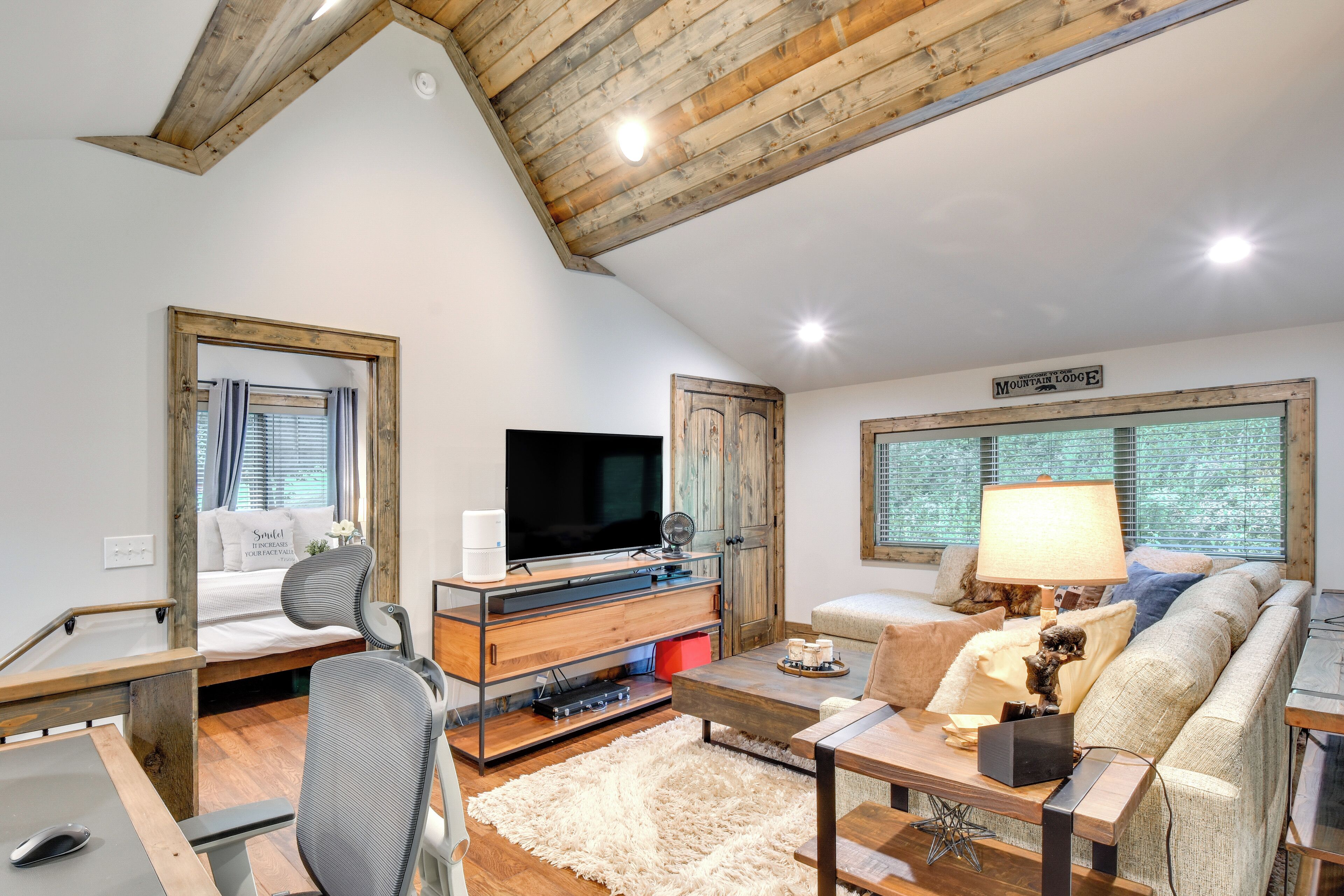 Una sala de estar acogedora con techo de madera, televisor de pantalla plana, sofá, mesa de centro y chimenea.