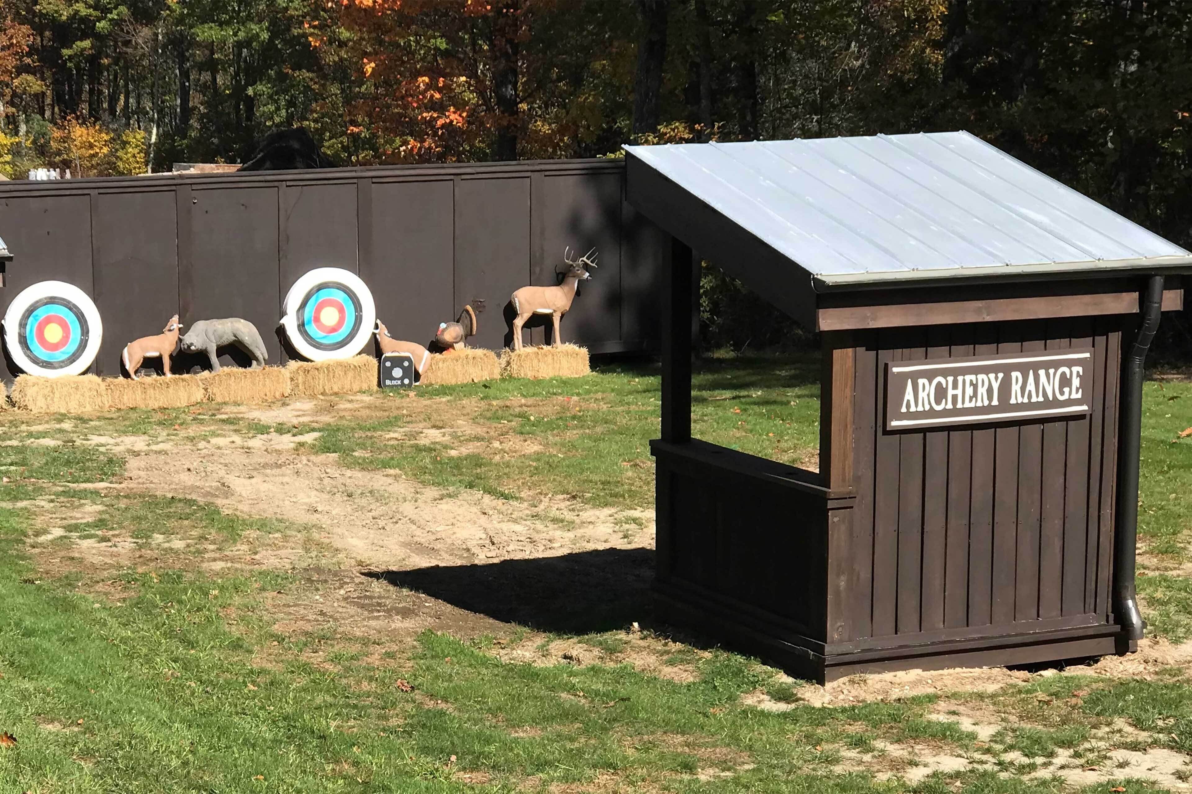 Un campo di tiro con bersagli e un ricovero in legno con la scritta "ARCHERY RANGE".