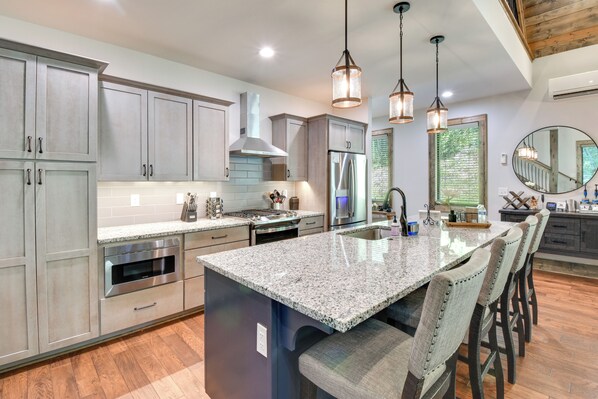 A modern kitchen with granite countertops, stainless steel appliances, and a large island with bar stools.