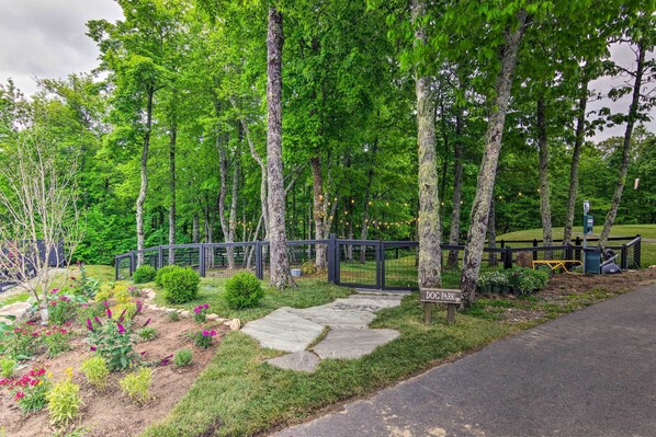A park with a stone pathway, trees, and a sign that reads "DOG PARK".