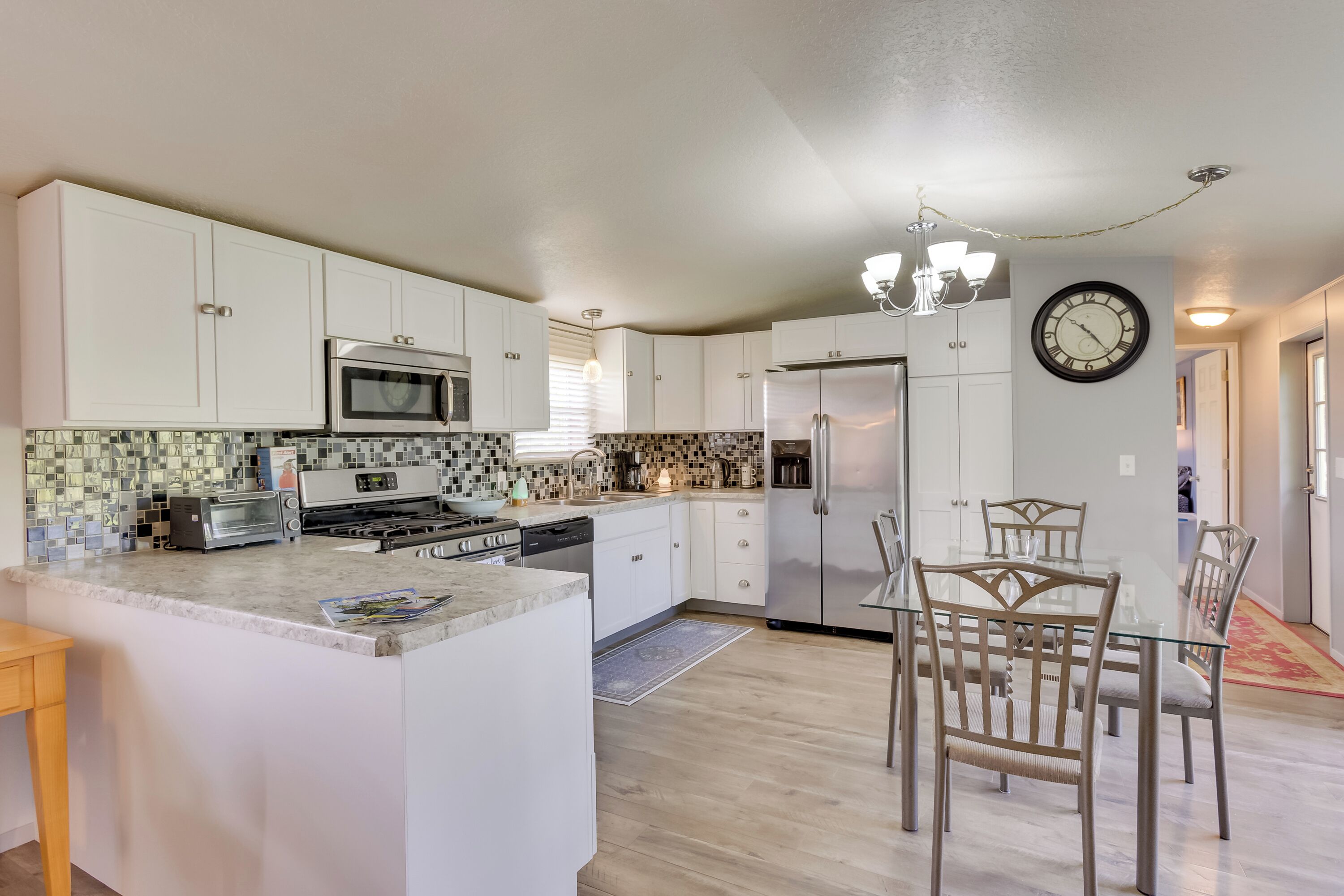 A modern kitchen with white cabinets, stainless steel appliances, and a dining area with glass tables and chairs.