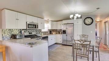 A modern kitchen with white cabinets, stainless steel appliances, and a dining area with glass tables and chairs.
