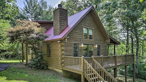 Une cabane en rondins avec une terrasse en bois et une cheminée.