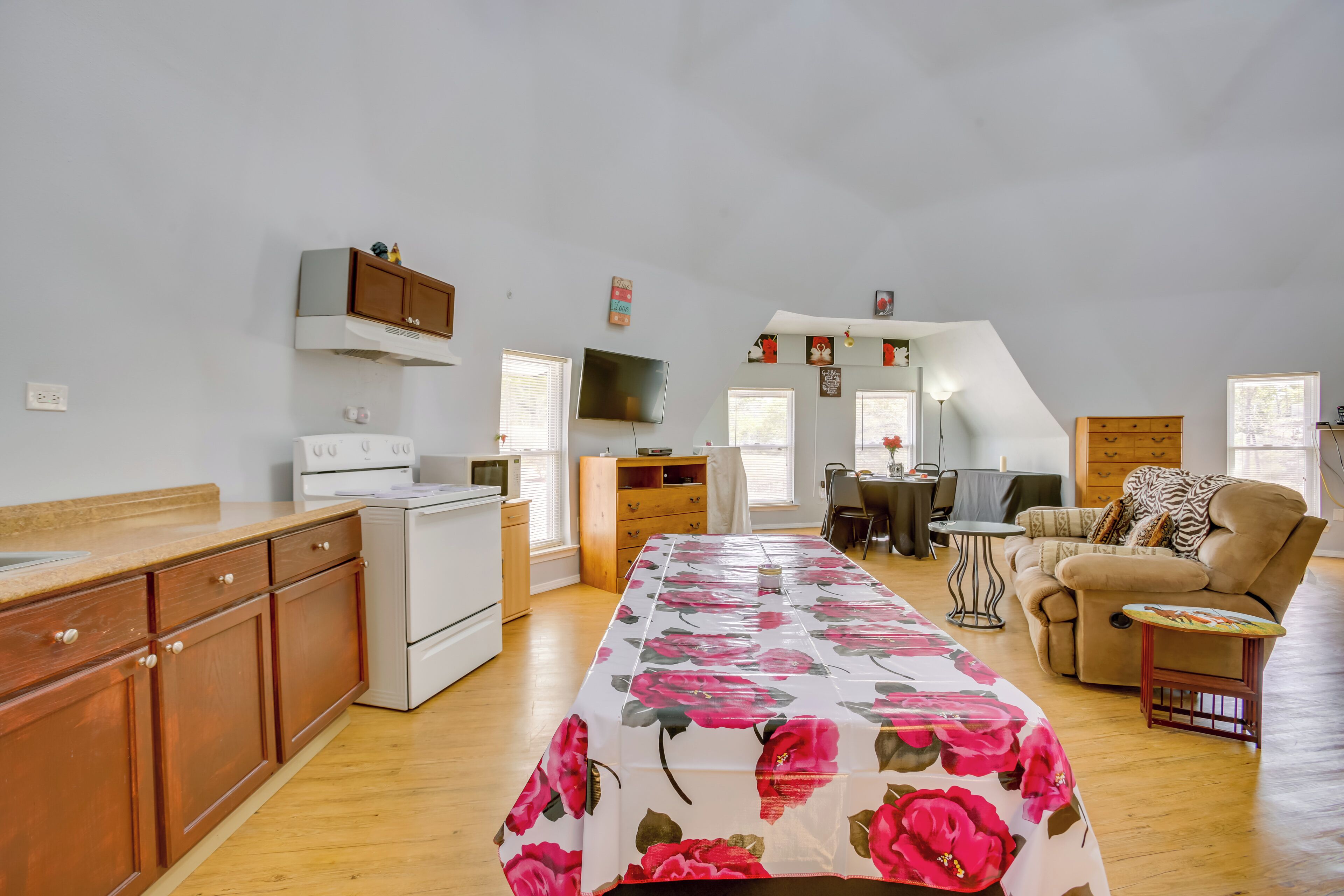 A spacious living area with a dining table, sofa, and kitchen appliances.