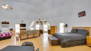 A spacious loft bedroom with a large bed, a desk, and a cozy seating area. - Remote Angie Vacation Rental Near Pearl River! (Angie)
