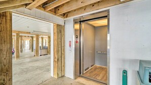 An interior with a wooden ceiling, a concrete floor, and a visible elevator. - Oak Island Condo - Walk to the Beach! (Oak Island)