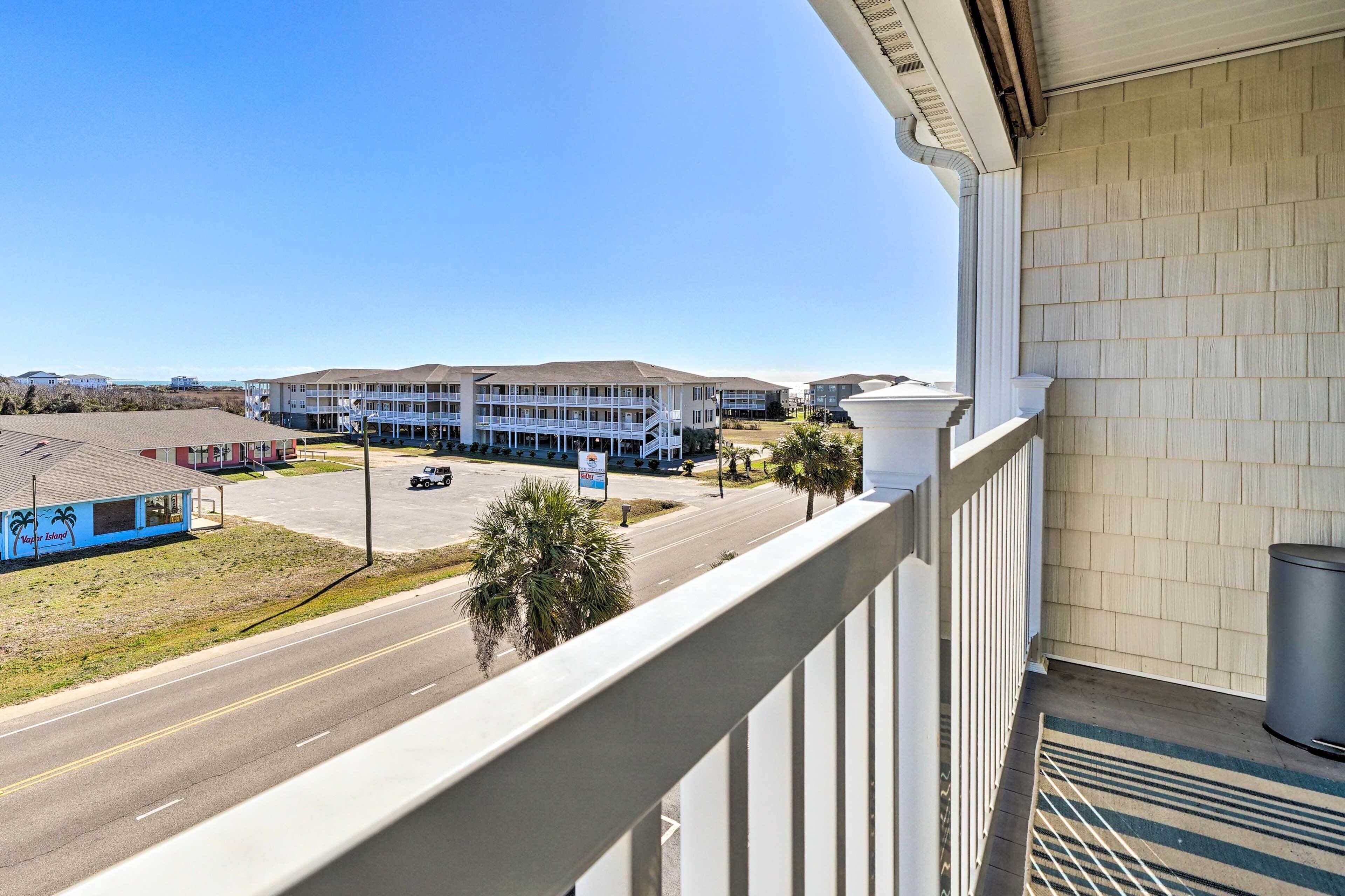A balcony overlooking a street with a building in the background.