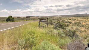 Un letrero que dice 'Yosemite's Jewelry Ranch' en un paisaje rural con una carretera y vegetación escasa.