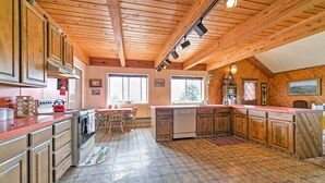 Una cocina con armarios de madera, una isla central y una zona de comedor con mesa y sillas.