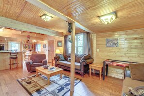 A cozy log cabin interior with a living room, dining area, and kitchen.