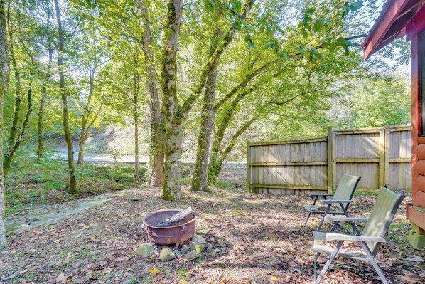 A rustic outdoor area with a fire pit, wooden chairs, and a wooden fence. - 'just Fur Relaxin' Sevierville Cabin w/ Hot Tub! (Sevierville)