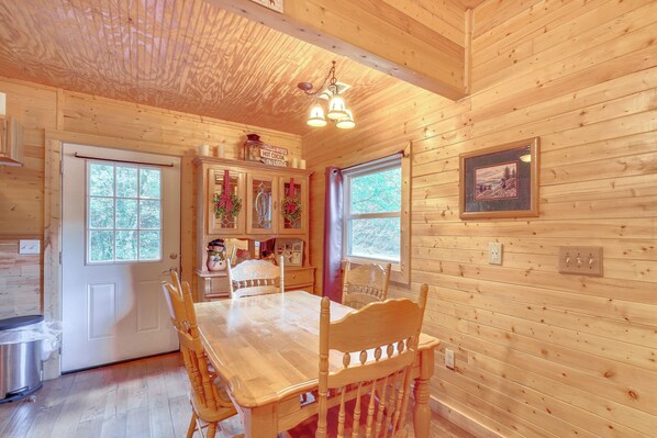 A wooden cabin interior with a dining table, chairs, a kitchen area, and a framed picture on the wall. - 'just Fur Relaxin' Sevierville Cabin w/ Hot Tub! (Sevierville)