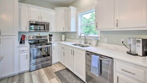 A modern kitchen with white cabinetry, stainless steel appliances, and a window providing natural light.