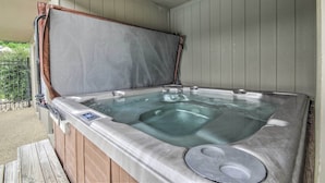 Un bain à remous doté d’une terrasse en bois et d’un couvercle en métal.