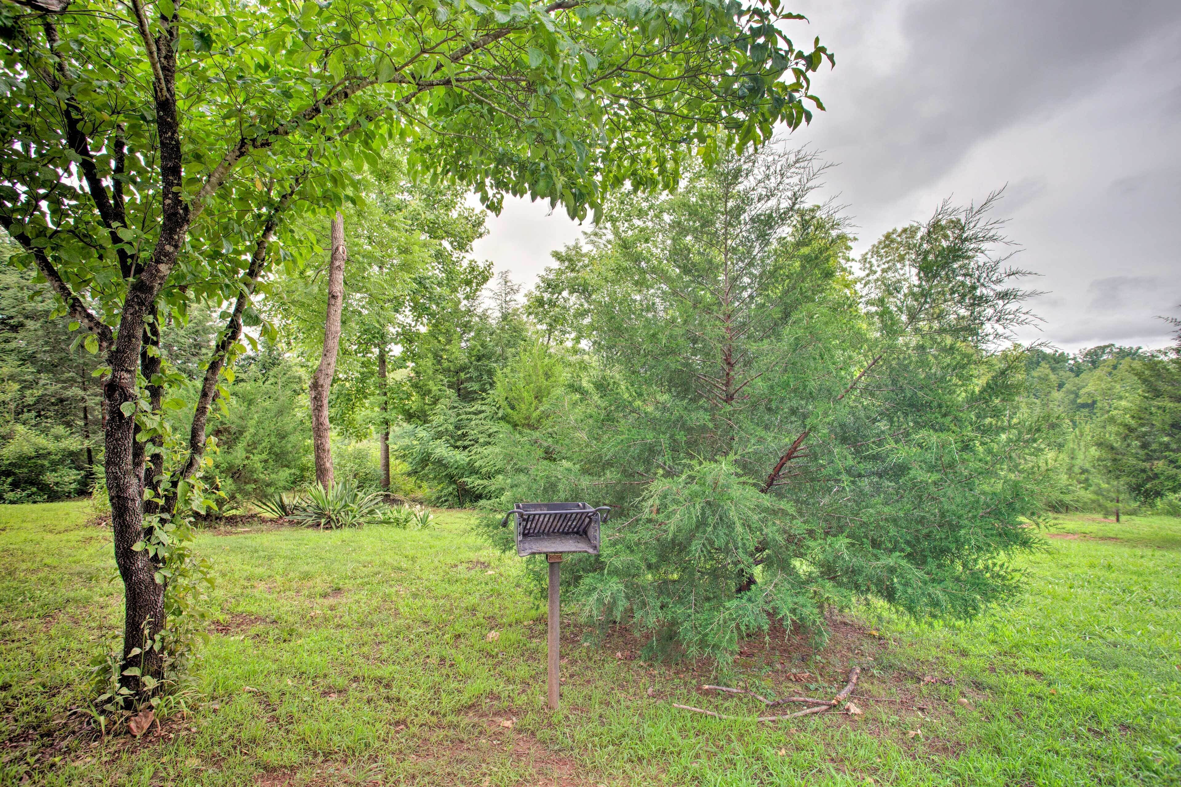 A bird feeder in a grassy area with trees in the background.