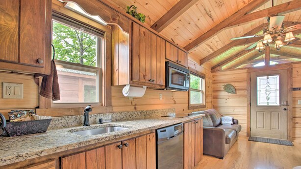 A wooden cabin interior with a kitchen featuring granite countertops, a built-in microwave, and a dishwasher. - Hike, Sip & Unwind! Mill Spring Cabin Near Winery (Mill Spring)