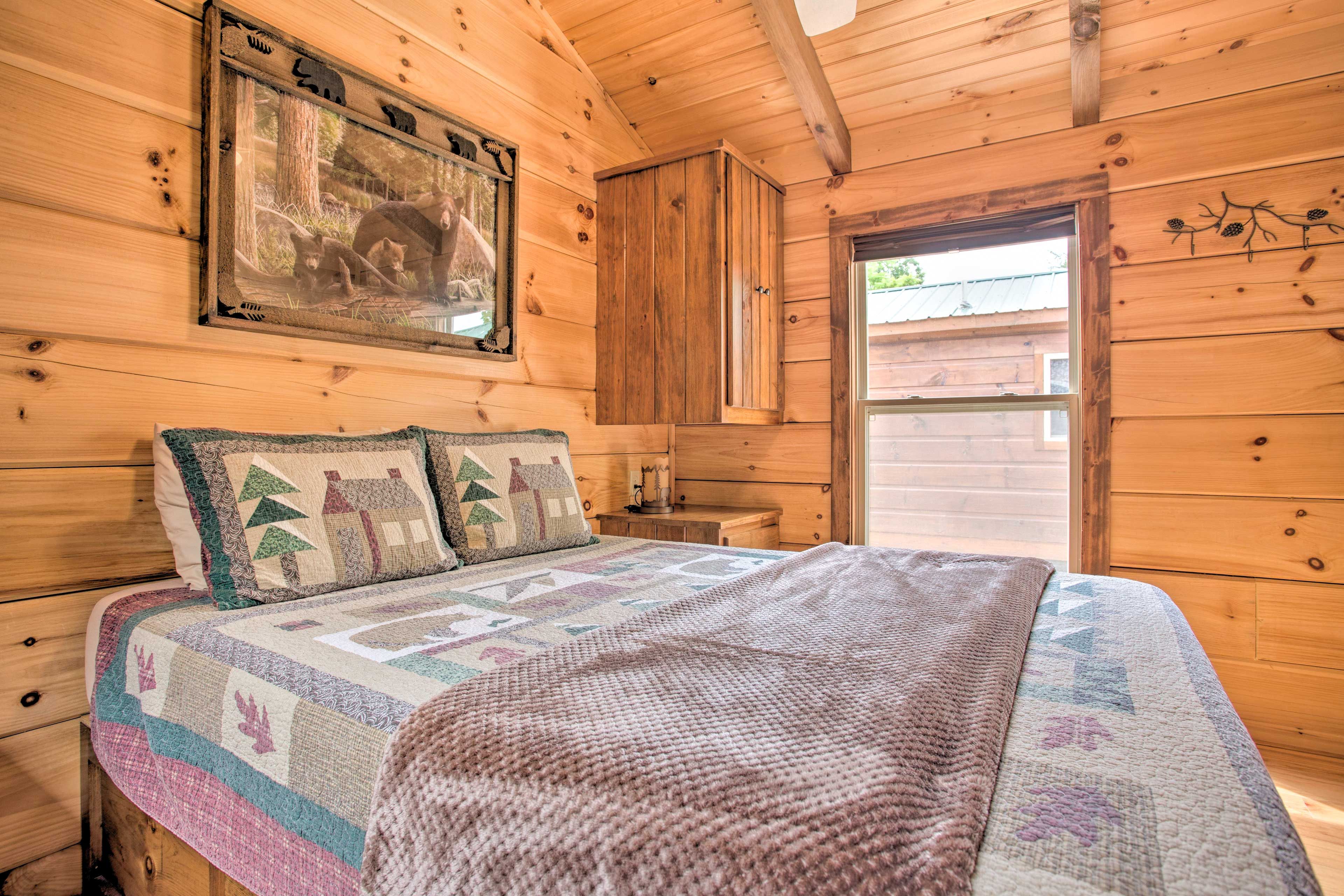 Une chambre à coucher dans un chalet en bois, avec un lit, une table de chevet, une armoire en bois et un tableau encadré au mur.