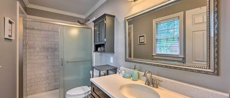 A modern bathroom with a walk-in shower, a toilet, a sink with a large mirror, and a vanity with cabinets.